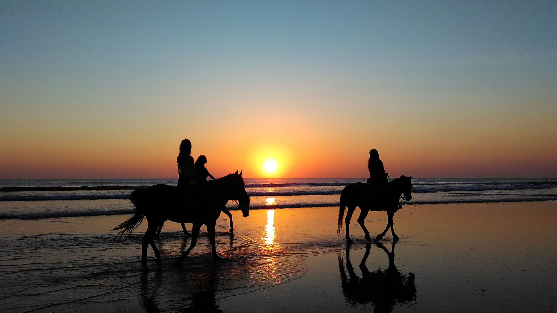 a cavallo sulla spiaggia al tramonto